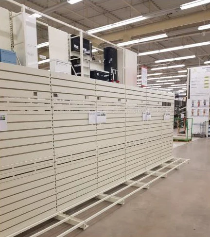 Pusty regał ekspozycyjny z metalowymi panelami i półkami w jasnym, przestronnym wnętrzu sklepu