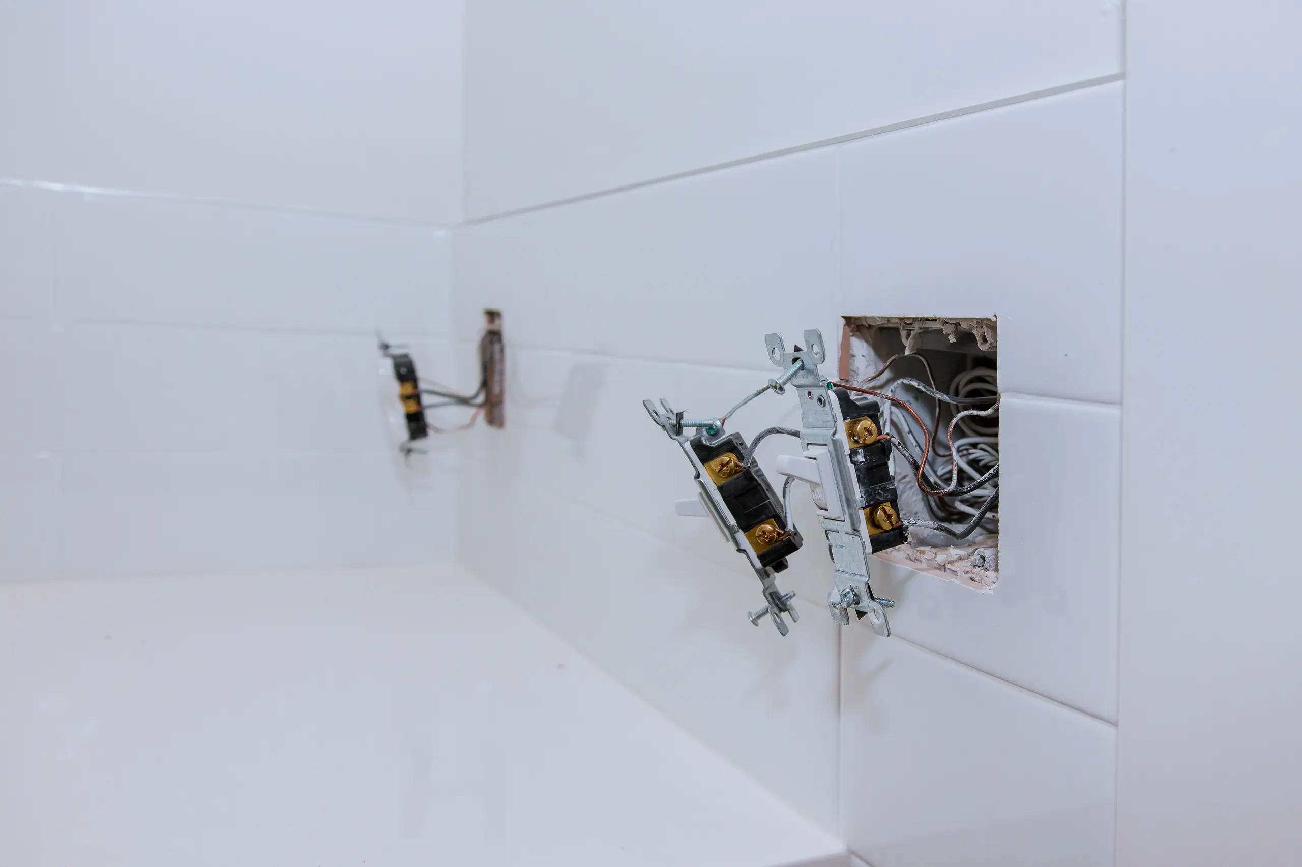 Instalacje elektryczne w łazience z widocznymi podtynkowymi puszkami i odsłoniętymi przewodami
